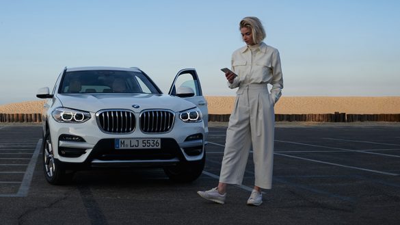 BMW X4 G02 Kataloge App Frau neben BMW 2021